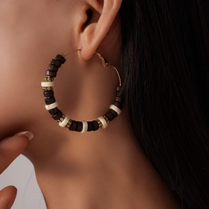 Detail shot of vintage bohemian hoop earrings with dark wood beads and gold spacers on model