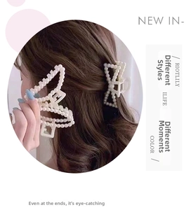 Detail of elegant pearl butterfly hair claw clip with cream finish on a metal base