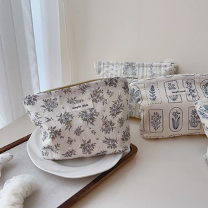 Detail view of cotton makeup bag featuring blue floral prints and a zipper closure