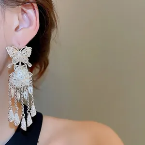 Silver hollow butterfly and flower long tassel drop earrings worn by a model