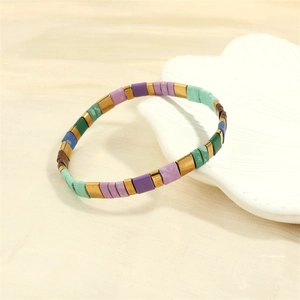 Detail of bohemian TILA beaded stretch bracelet with colorful matte enamel tiles and gold accents