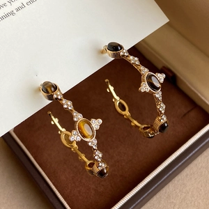 Dettaglio di orecchini vintage a cerchio C in oro con occhio di tigre in scatola velluto
