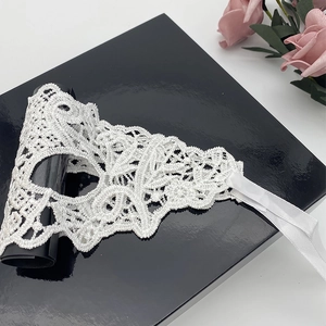 Detailed view of intricate white floral lace and satin ribbon on a black gift box
