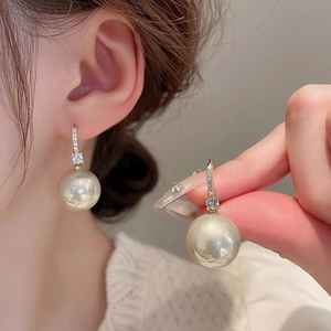 Close-up of champagne pearl earrings with sparkling crystal accents on model