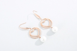 Macro view of heart-shaped hollow earrings with rose gold finish and white pearl drops