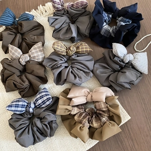 Detailed view of checkered and solid bow scrunchies on a textured tabletop