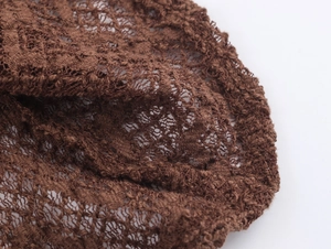 Macro shot of dark brown knitted lace fabric showing intricate hollow texture details