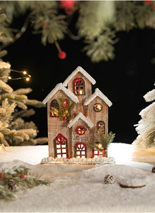 Détail d'un chalet de Noël lumineux en bois avec éclairage LED et décorations de neige