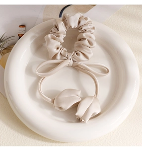 Close-up of silk tulip ribbon hair scrunchie in a white ceramic dish