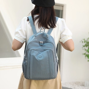 Grey-blue large capacity nylon backpack for women being worn by a model in a natural setting