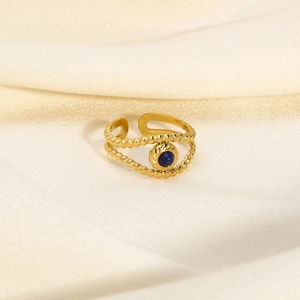 Detailed close-up of a vintage gold-plated ring with a central blue gemstone on silk