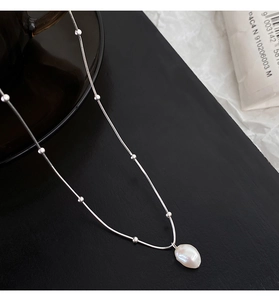 Detailed close-up of a Baroque pearl pendant on a silver-tone beaded snake chain necklace