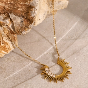 Vue macro du collier avec pendentif soleil doré et zircons sur un fond de pierre