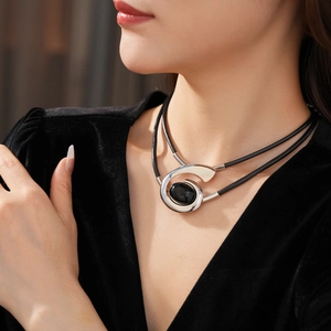 Detail of double-layer black leather necklace with oval black stone and silver frame