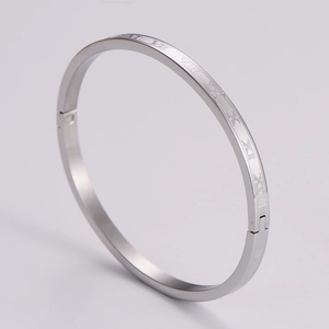 Detail of silver stainless steel bangle featuring engraved Roman numerals and side hinge
