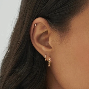 Close-up of minimalist gold hoop earrings set with pink gemstone on ear for daily wear