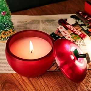 Bougie parfumée en forme de pomme avec couvercle allumée sur une table de fête