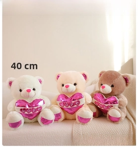 Three plush teddy bears in 40cm size with shiny LOVE hearts on a beige sofa