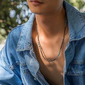 Close-up of men's bohemian beaded necklace with turquoise stones and black metallic beads