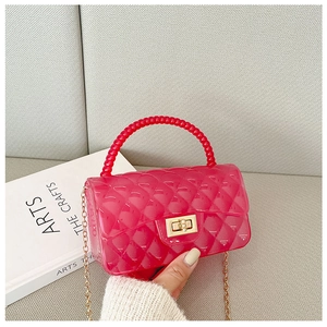 Close-up of rose red jelly bag with quilted pattern, bead handle and gold chain strap