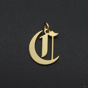 Macro shot of a vintage golden Gothic letter C pendant with a hanging ring detail