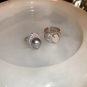 French retro oval rings with grey pearl and zircon insets in white ceramic tray
