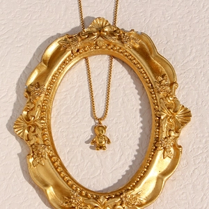 Detail view of a 3D gold balloon bear pendant displayed inside a vintage golden frame