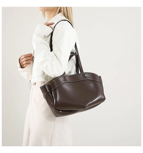 Dettaglio di una grande borsa tote in pelle cioccolato con cuciture a contrasto e bordo curvo
