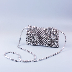 Macro detail of silver woven chain mail texture and metallic beads on a cross-body bag