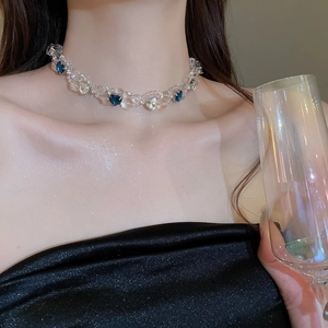 Detail of beaded necklace with blue heart crystal on model neck for party wear