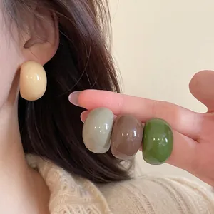 Minimalist acrylic C-shaped earrings in Morandi colors shown on model and held in hand