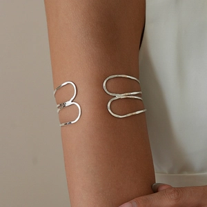 Close-up of silver multilayer geometric arm cuff with hand-hammered texture on model