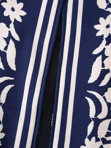 Dettaglio macro del tessuto a maglia blu con motivi floreali bianchi e strisce verticali