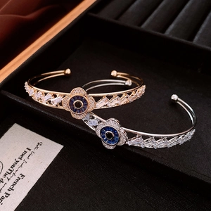 Detail of gold and silver clover evil eye bracelets with zircons on black velvet tray
