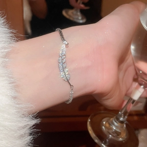 Detail of silver feather bracelet with pavé cubic zirconia worn on female wrist