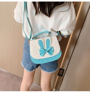 Detail of girl's blue and white crossbody bag with cute bunny ears and bow on leather