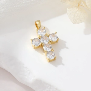 Macro detail of 14K gold plated cross pendant with clear cubic zirconia on stone