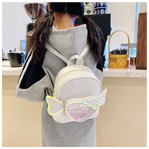 Detail of white children's backpack featuring sequin pocket and angel wing decorations