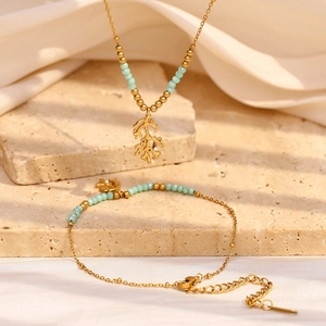 18K gold-plated branch pendant necklace and turquoise bead bracelet set on stone base