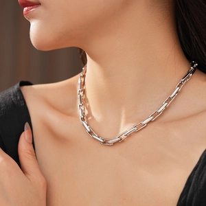 Close-up of silver geometric chain necklace showing the modern link design on model