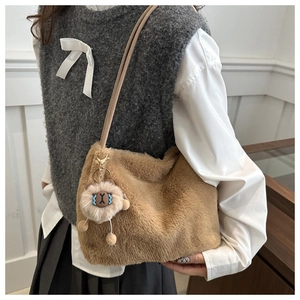 Detail of khaki plush tote bag with furry texture and cute cartoon charm accessory