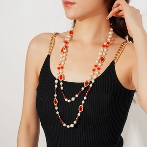 Close-up of vintage multi-layer gold chain necklace with white pearls and red gemstones