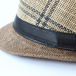 Beige and brown woven straw fedora hat featuring a black silk ribbon and dense stitching