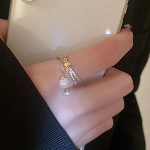 Detail of gold-plated double-layer crossover ring with zircons and pearl tassels