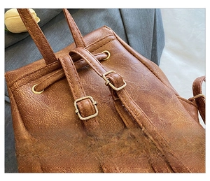 Macro shot of brown retro PU leather backpack showing adjustable straps and gold metal buckles