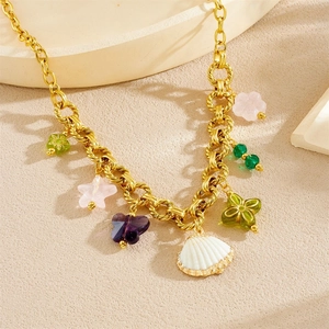 Collier à grosse chaîne dorée avec breloques coquillages et papillons colorés au soleil