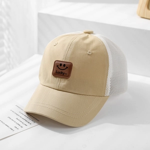 Detail of khaki mesh baseball cap with smile patch and Lucky text on a sunny white table