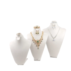 Three white velvet bust displays featuring vintage and modern gemstone jewelry sets