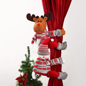 Detailed view of festive reindeer and snowman plush Christmas curtain tiebacks on red fabric.