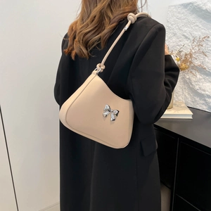 Minimalist beige PU leather shoulder bag with a metal bow decoration shown on a model